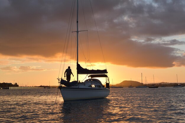 Homme sur petit yacht à la lumière du coucher du soleil