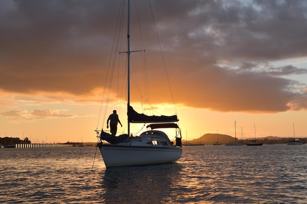 Homme sur petit yacht à la lumière du coucher du soleil