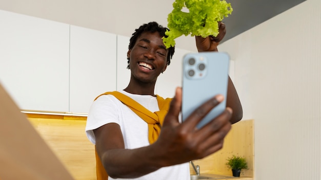 Photo gratuite homme de plan moyen cuisinant avec un smartphone