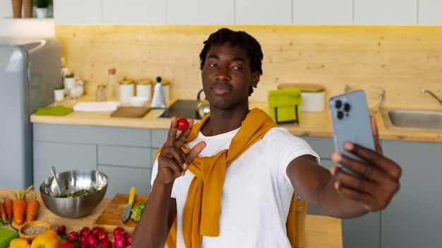 Homme de plan moyen cuisinant avec un smartphone