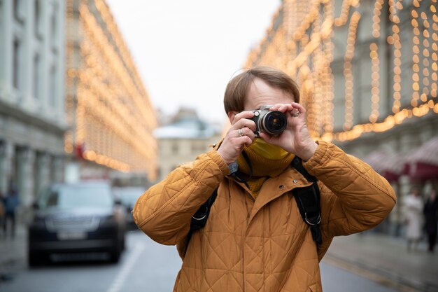 Homme de plan moyen prenant des photos avec un appareil photo