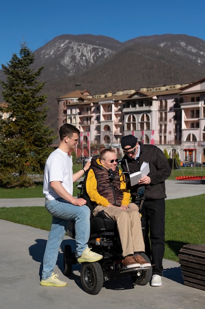 Photo gratuite homme plein coup aidant un ami handicapé à lire