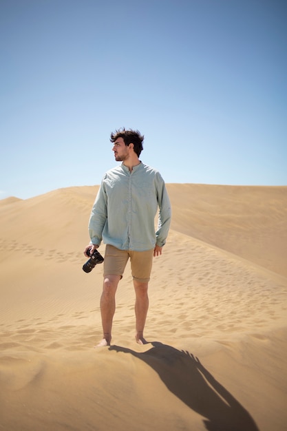 Homme plein coup avec appareil photo dans le désert