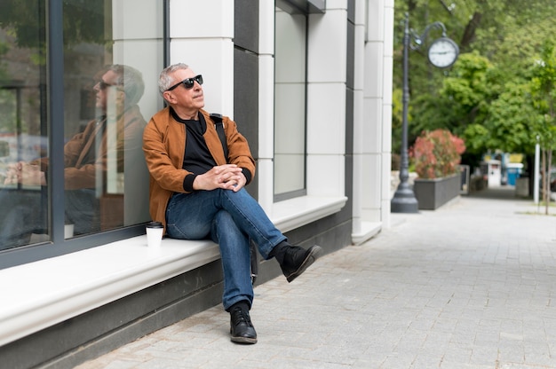 Photo gratuite homme plein coup assis à l'extérieur
