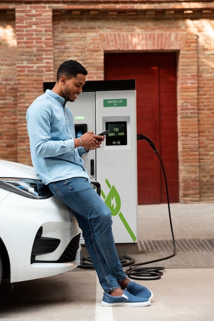 Photo gratuite homme plein coup attendant que la voiture se charge