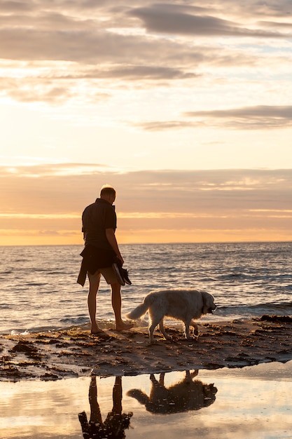 Homme plein coup avec un chien mignon sur la plage