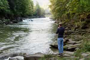 Photo gratuite homme plein coup debout au bord de la rivière