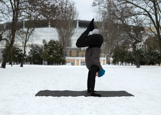 Homme plein coup faisant du yoga par temps froid