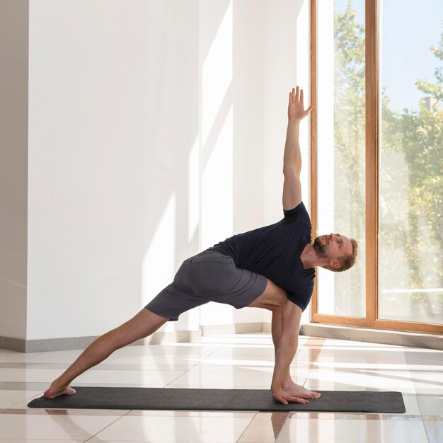 Homme plein coup faisant le triangle pose à l'intérieur