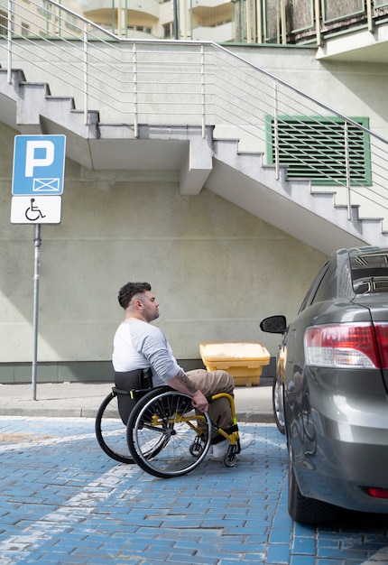 Photo gratuite homme plein coup en fauteuil roulant près de voiture