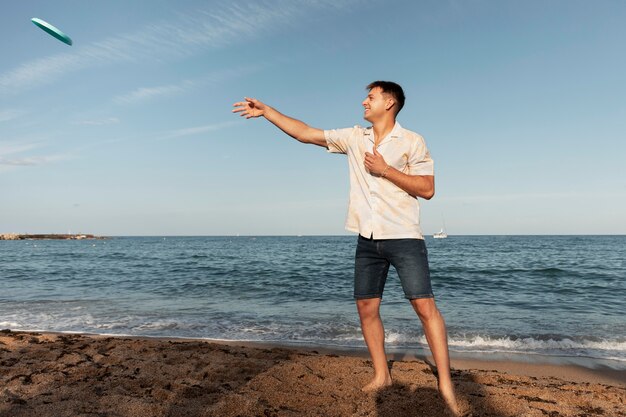 Homme plein coup jouant à la plage