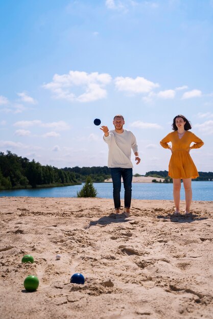 Homme plein coup lançant une balle sur la plage