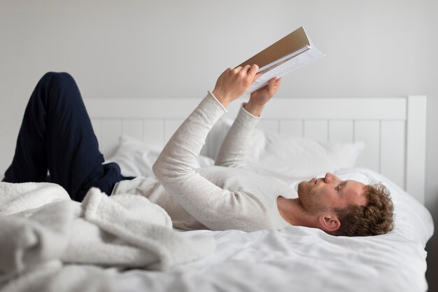 Homme plein coup lisant au lit