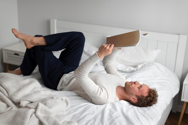 Homme plein coup lisant un livre à la maison