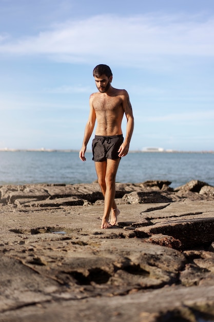 Photo gratuite homme plein coup avec poitrine velue au bord de la mer