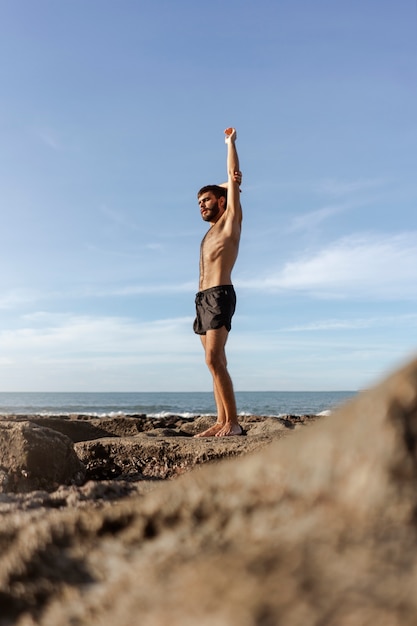 Photo gratuite homme plein coup avec poitrine velue au bord de la mer