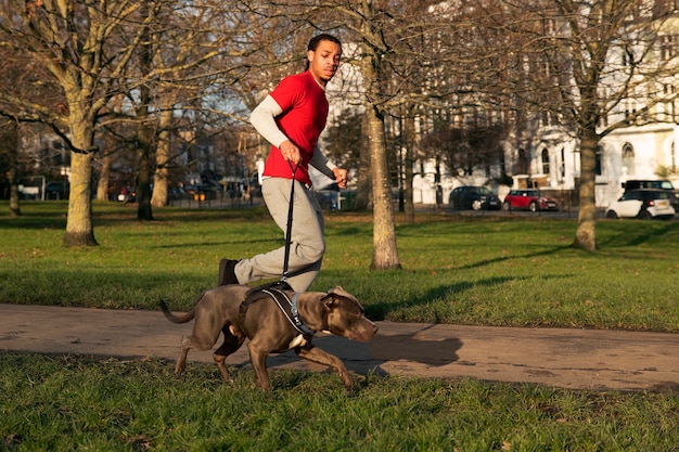 Photo gratuite homme plein coup qui court avec un chien à l'extérieur