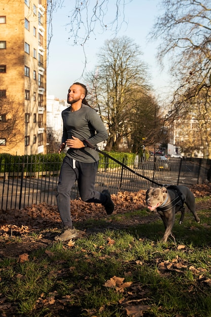 Photo gratuite homme plein coup qui court avec un chien à l'extérieur