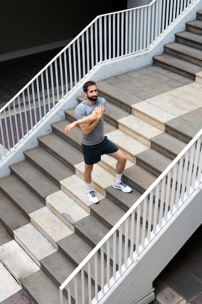 Photo gratuite homme plein coup qui s'étend dans les escaliers