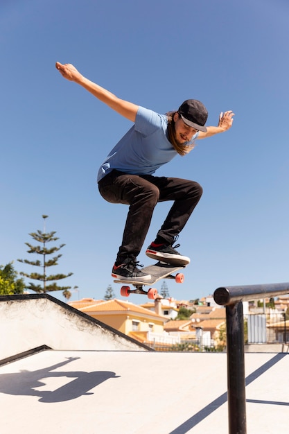 Homme plein coup sautant avec skateboard