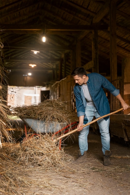 Photo gratuite homme plein coup travaillant avec une fourche