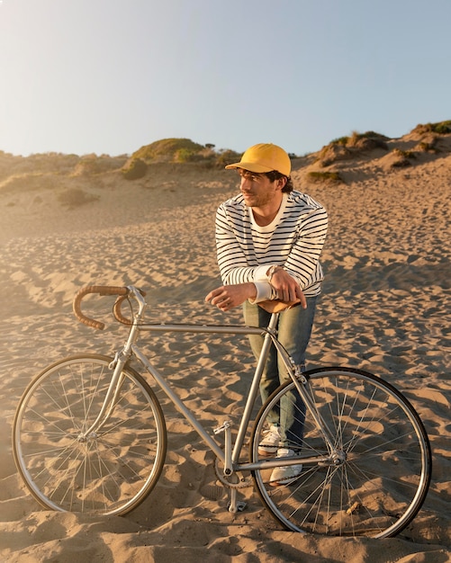 Homme plein coup avec vélo à la plage