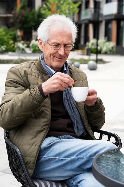 Homme plus âgé dans la ville ayant une tasse de café