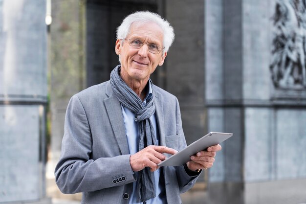 Homme plus âgé élégant dans la ville à l'aide d'une tablette