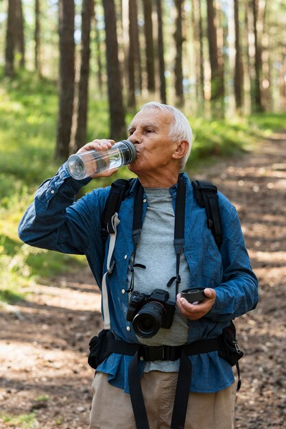 Un homme plus âgé reste hydraté tout en explorant le plein air