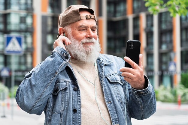 Homme plus âgé avec smartphone à l'extérieur de la ville