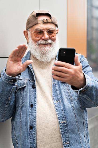 Homme plus âgé utilisant un smartphone à l'extérieur de la ville pour un appel vidéo