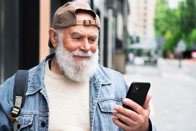 Homme plus âgé utilisant un smartphone à l'extérieur de la ville