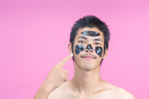 L’homme a pointé sa main sur son visage avec des produits de beauté noirs et une rose.