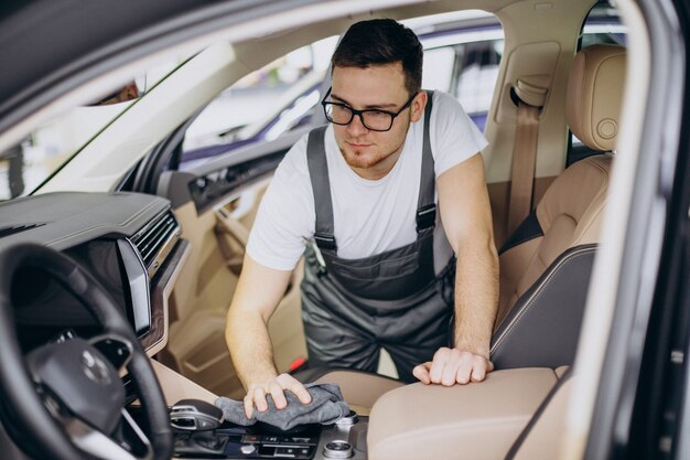 Homme polissant la voiture à l'intérieur au service de voiture