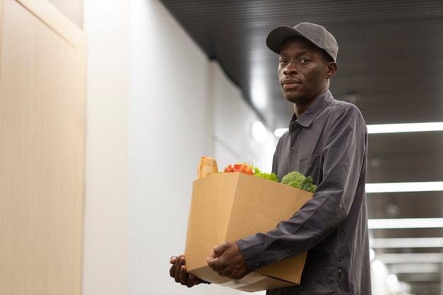 Photo gratuite homme portant une boîte d'épicerie plan moyen