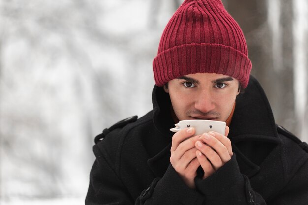 Homme portant un chapeau rouge tenant une tasse de thé