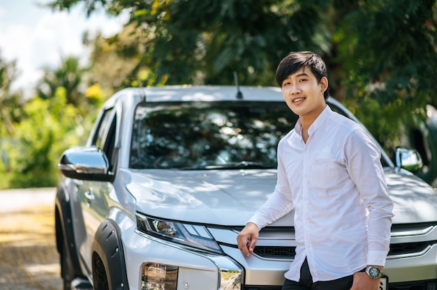 Photo gratuite un homme portant une chemise blanche et debout devant une voiture