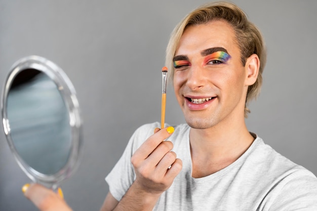 Homme portant des cosmétiques de maquillage et tenant une brosse