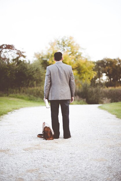 Homme portant un costume d'affaires debout sur un chemin tout en tenant la Bible