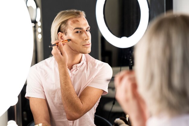 Homme portant du maquillage faisant son contour du visage