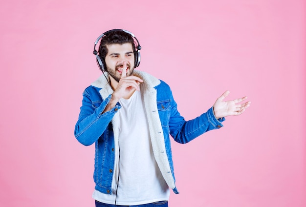 Homme portant des écouteurs pointant vers la personne à droite