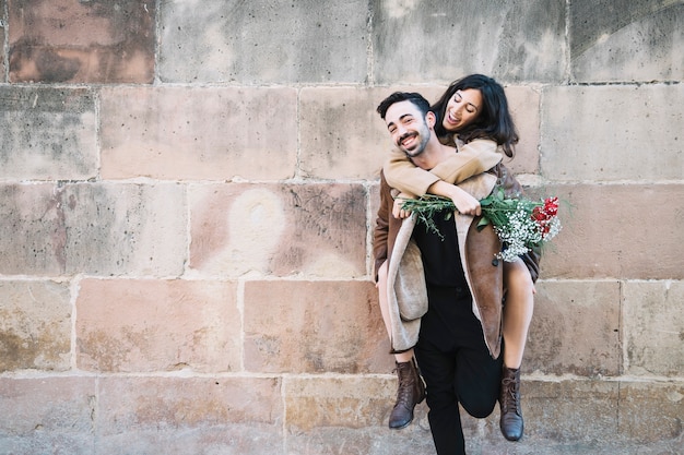 Homme portant une femme sur le dos près du mur