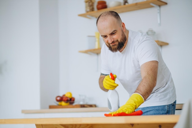 Photo gratuite homme portant des gants en caoutchouc nettoyant à la cuisine