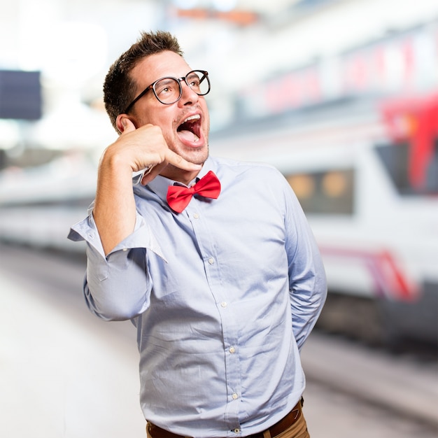 Homme portant un noeud papillon rouge. Faire un geste de téléphone.