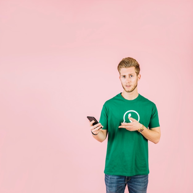 Homme portant des t-shirt icône whatsapp gesticulant tout en tenant le téléphone portable
