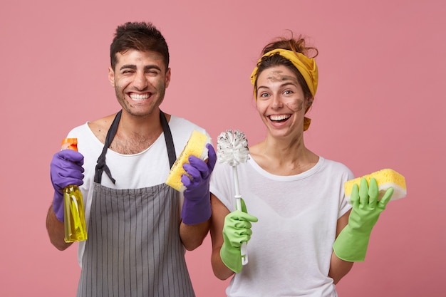 Homme portant un tablier et femme en T-shirt blanc souriant largement d'être heureux de nettoyer