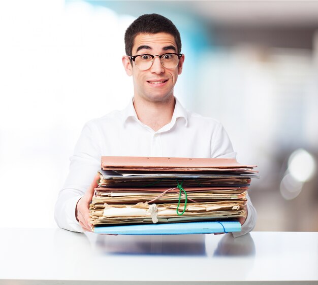 Homme portant un tas de dossiers dans un bureau