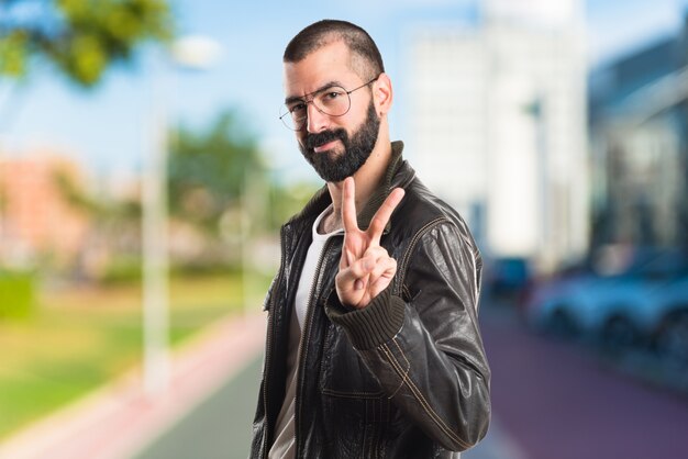 Homme portant une veste en cuir faisant un geste de victoire