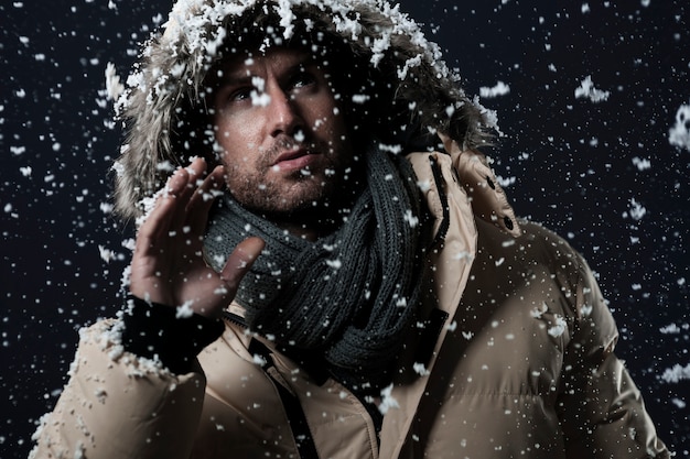 homme portant une veste d'hiver pendant qu'il neige