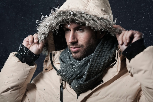 homme portant une veste d'hiver pendant qu'il neige